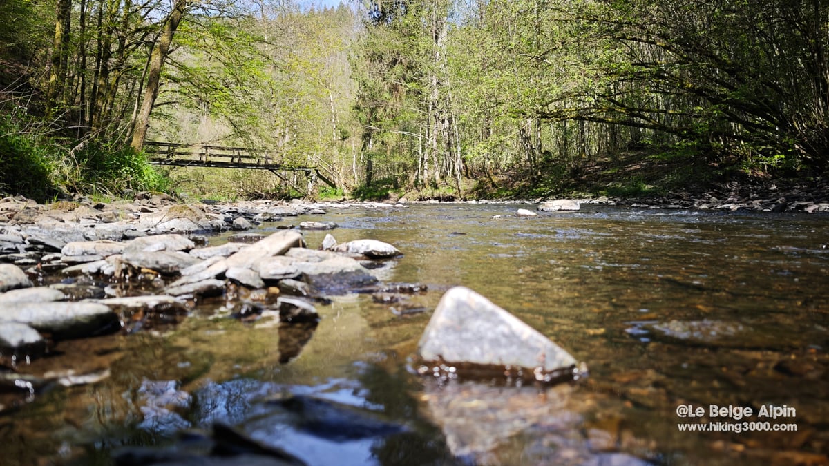 Lit caillouteux de la Lieser vu de tres bas, gros galets au premier plan, passerelle en arriere-plan