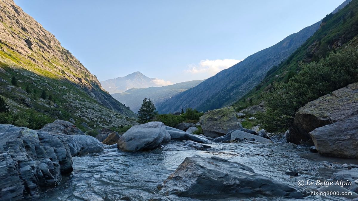 Le torrent descend en cascades, un sommet dentelé au fond du vallon