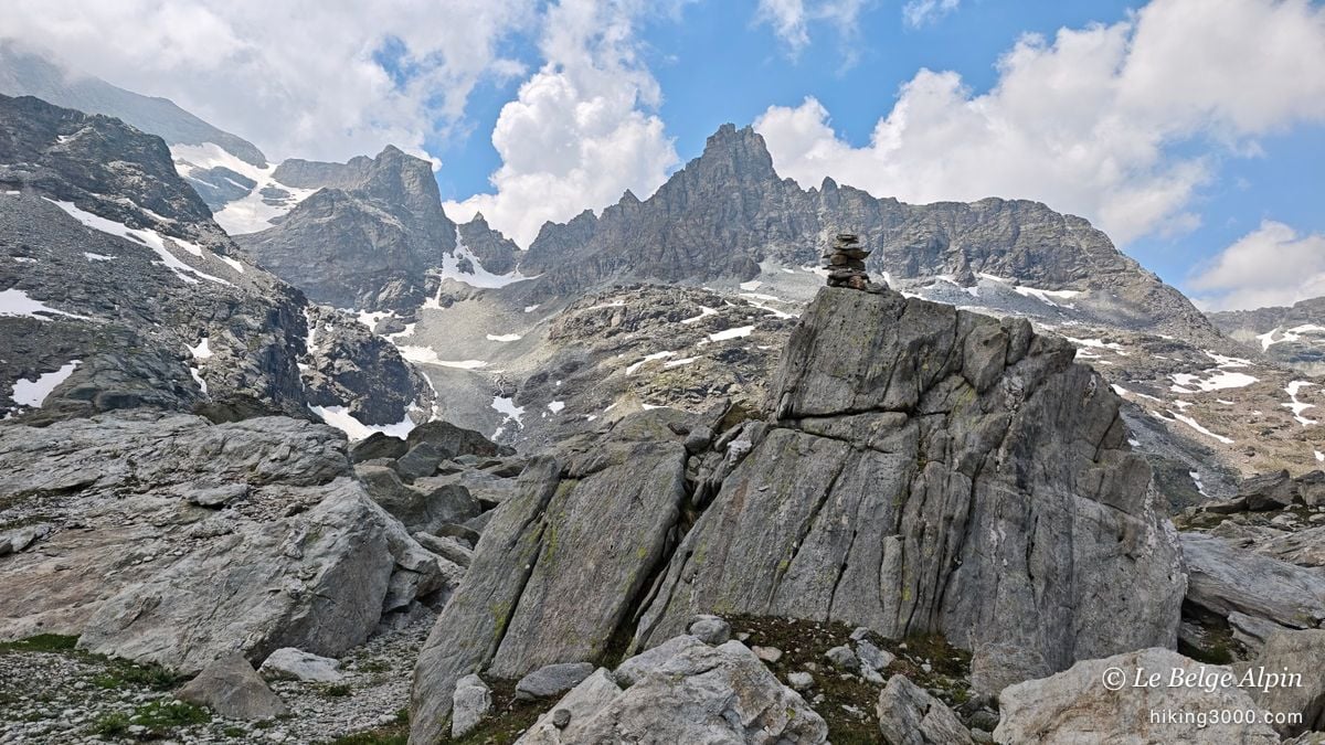 Un cairn sur un bloc, et les aiguilles déchiquetées derrière