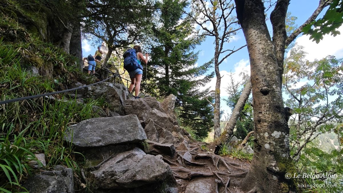 A rocky section fitted with a cable, where the trail steepens