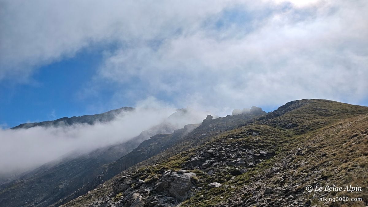 Clouds spill over the ridge, high-mountain atmosphere